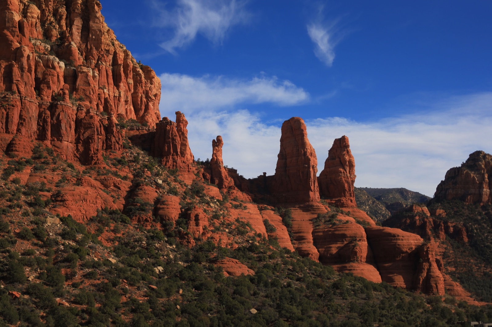 Red sandstone spires and cliffs above juniper-covered slopes near Sedona, Arizona