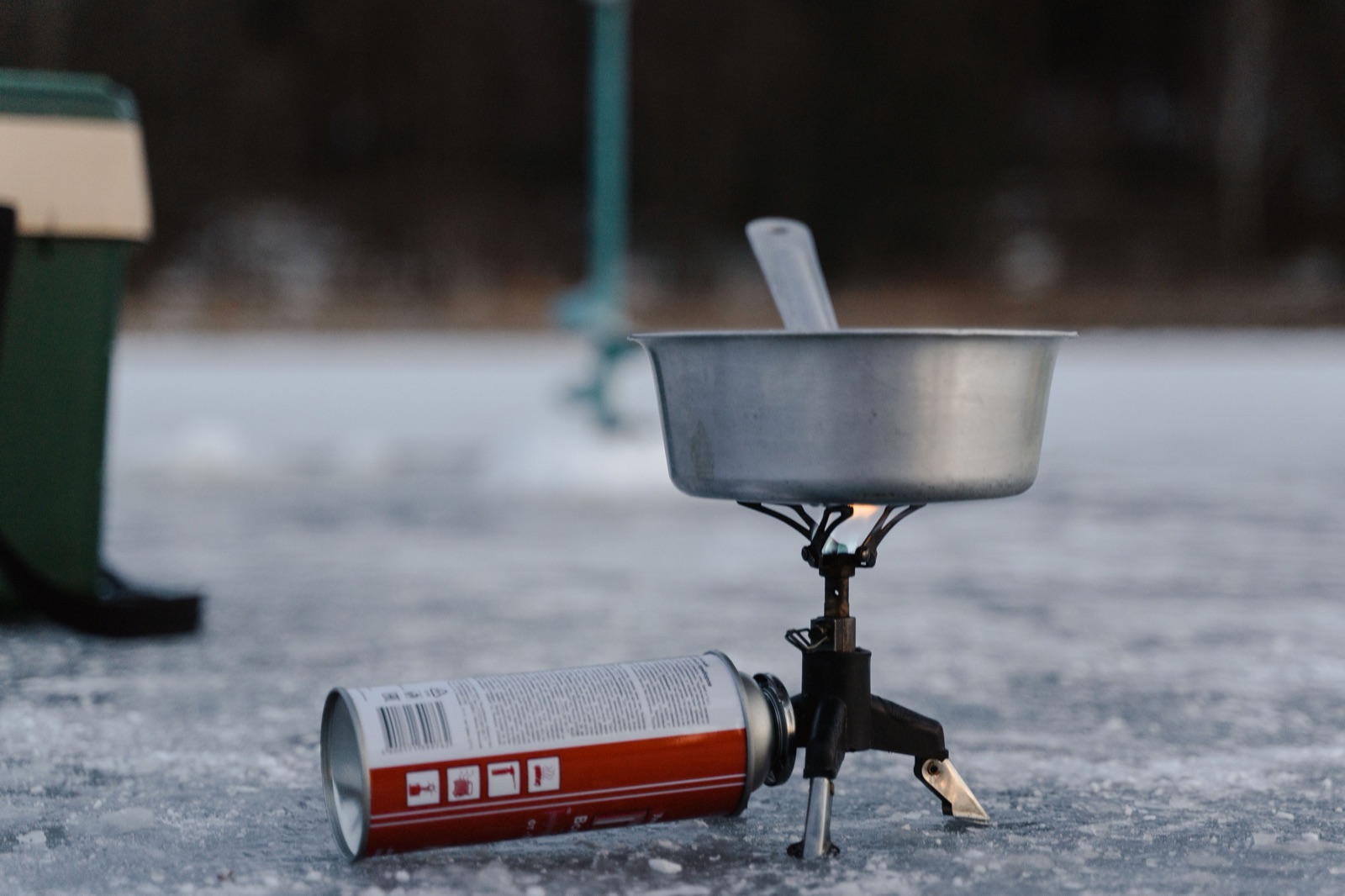 A metal pot on a small camping stove connected to a gas canister, outdoors