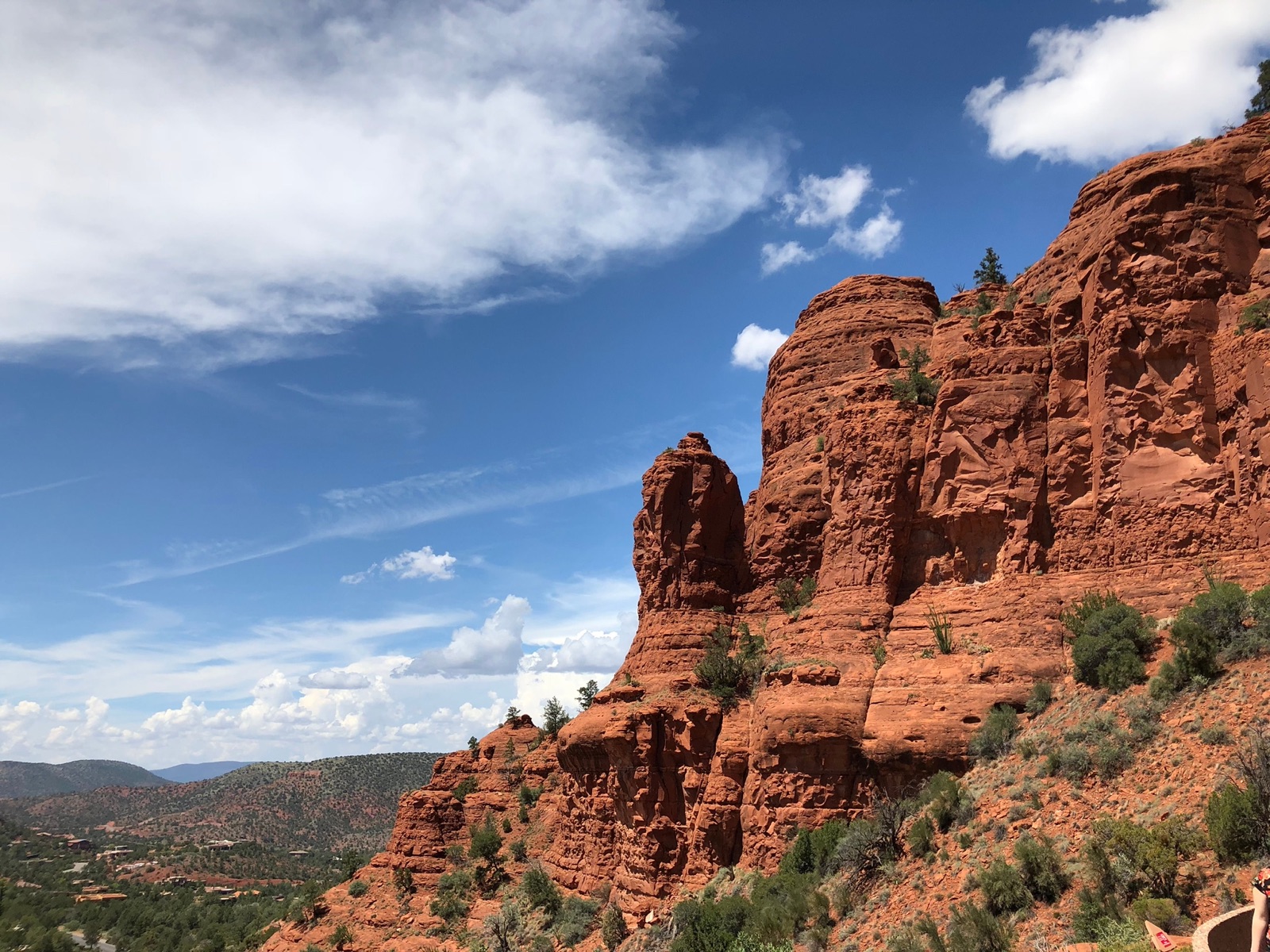Red rock buttes and green juniper slopes under a blue sky in Sedona, Arizona